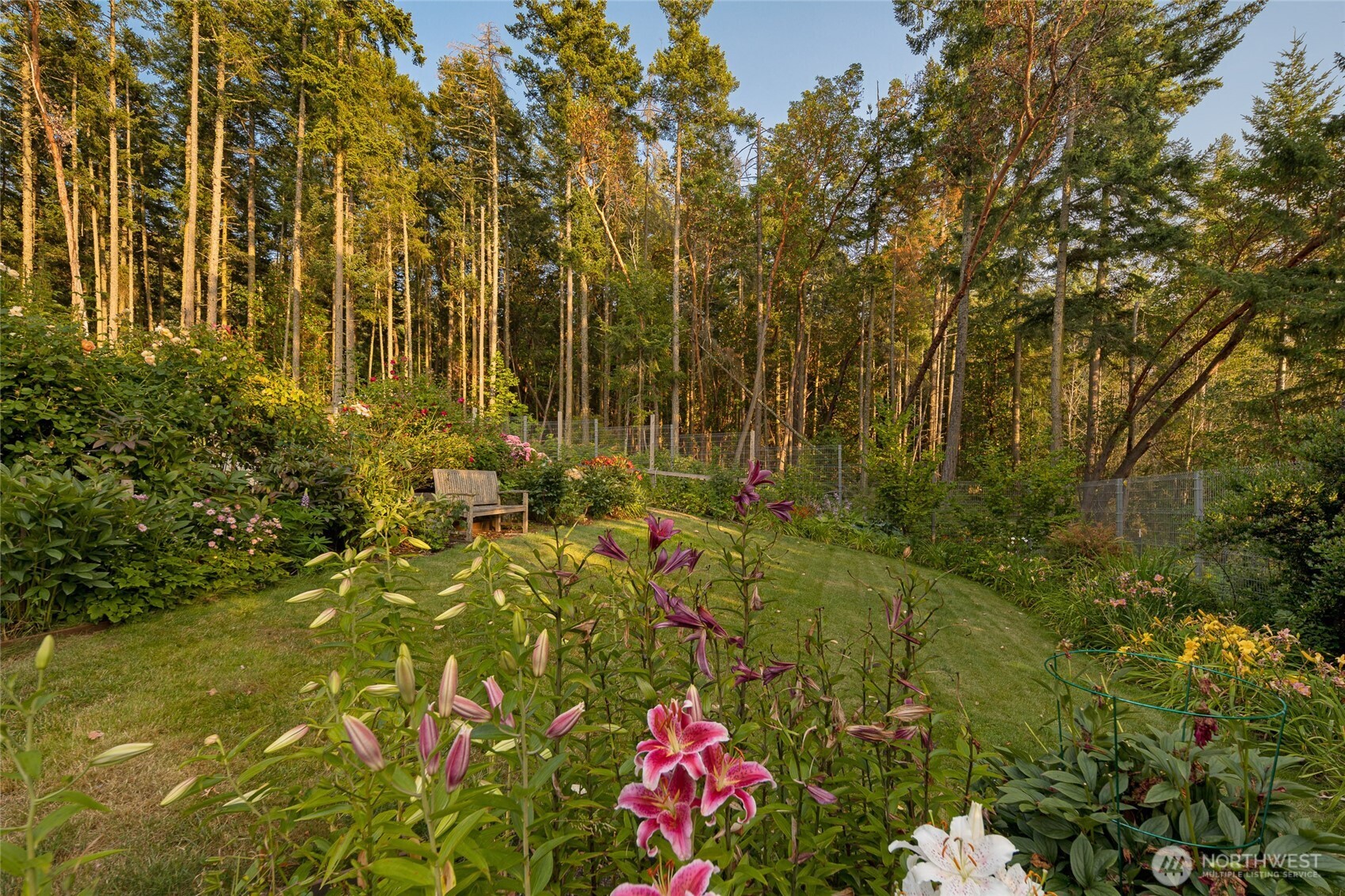 A vibrant flower garden surrounded by native forest offers a peaceful retreat, blending curated landscaping with the natural beauty that defines San Juan Island living.