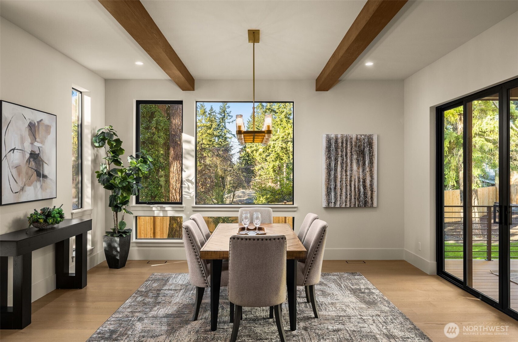 Large dining room with wood beam accents and floor to ceiling windows
