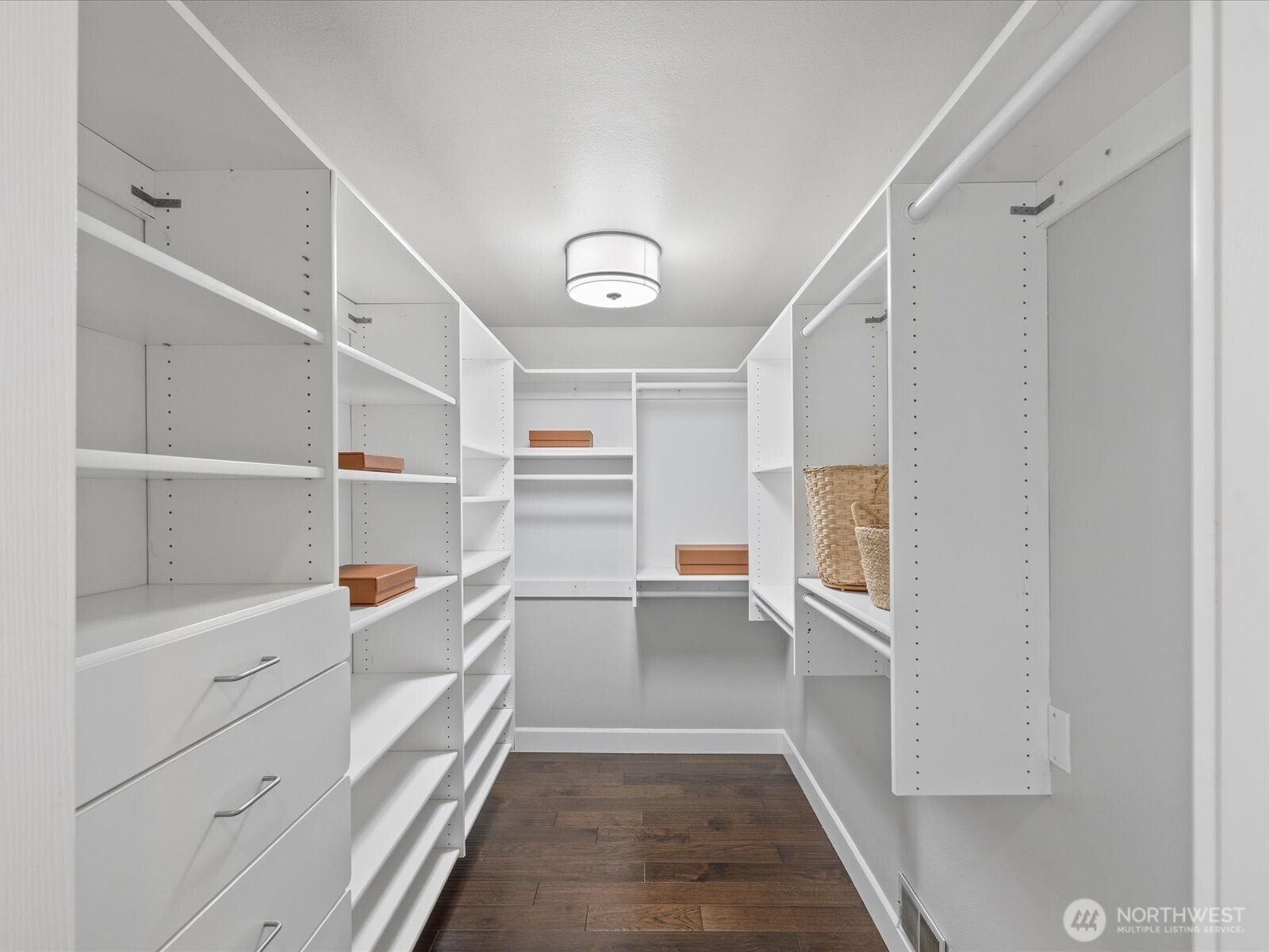 Walk-in closet with built-in shelving, drawers, and hardwood flooring