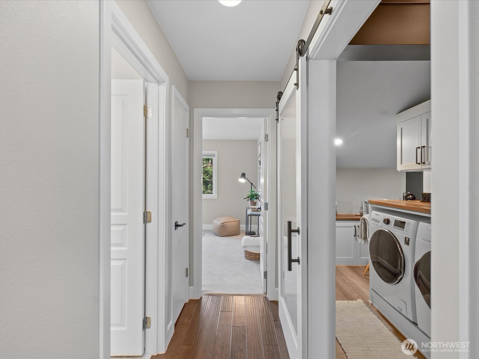 Interior hallway with hardwood flooring and adjacent laundry room with washer and dryer