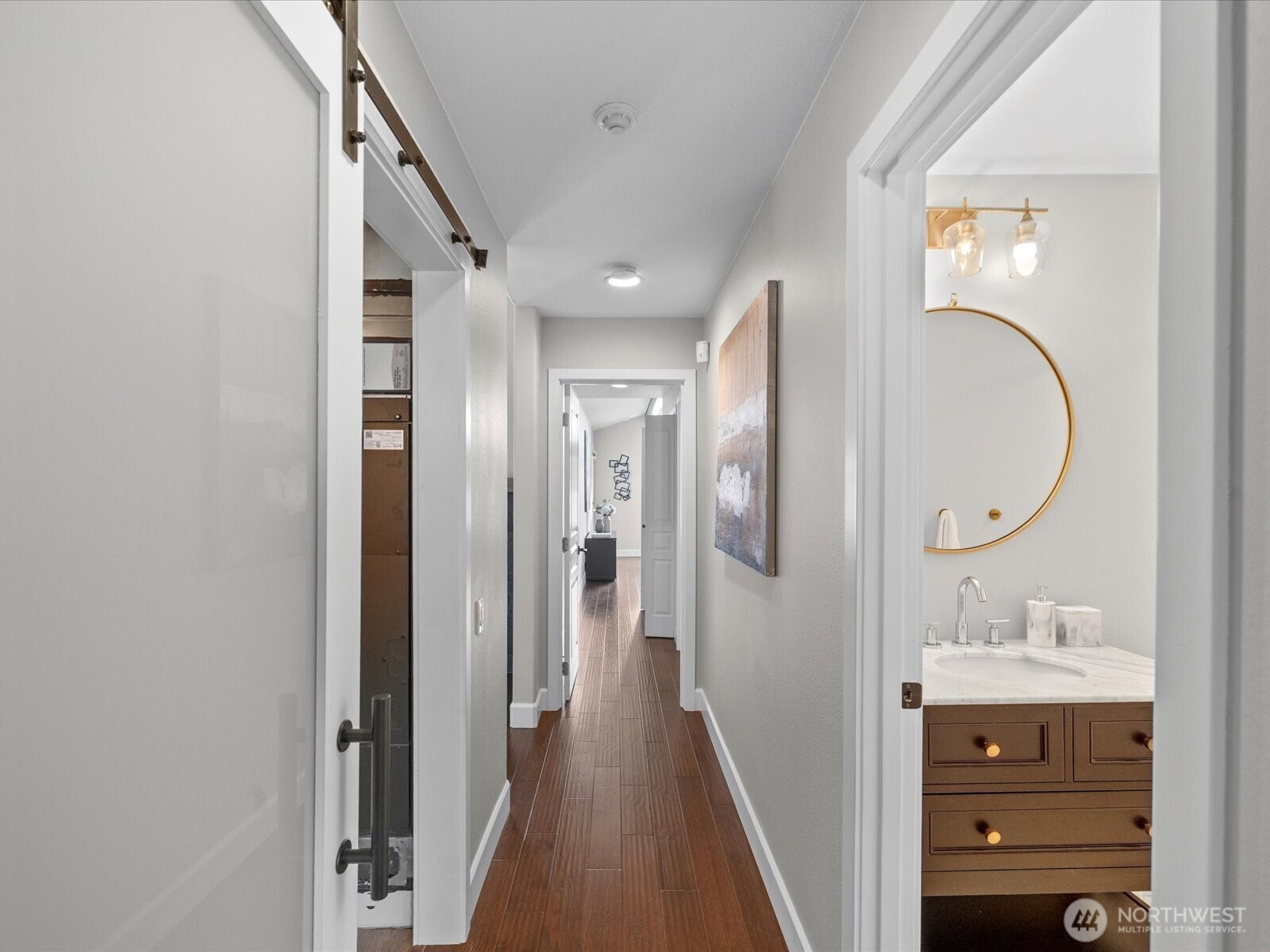 Interior hallway with hardwood flooring and access to bedrooms and bathroom