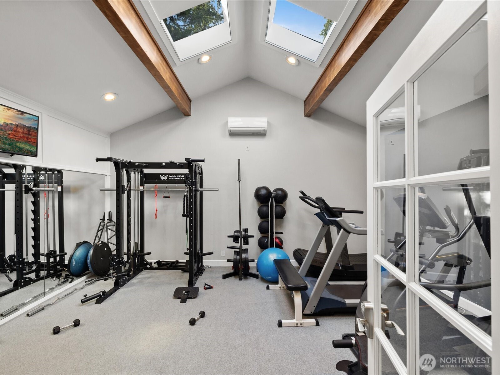 Community fitness room with exercise equipment, skylights, and vaulted ceilings