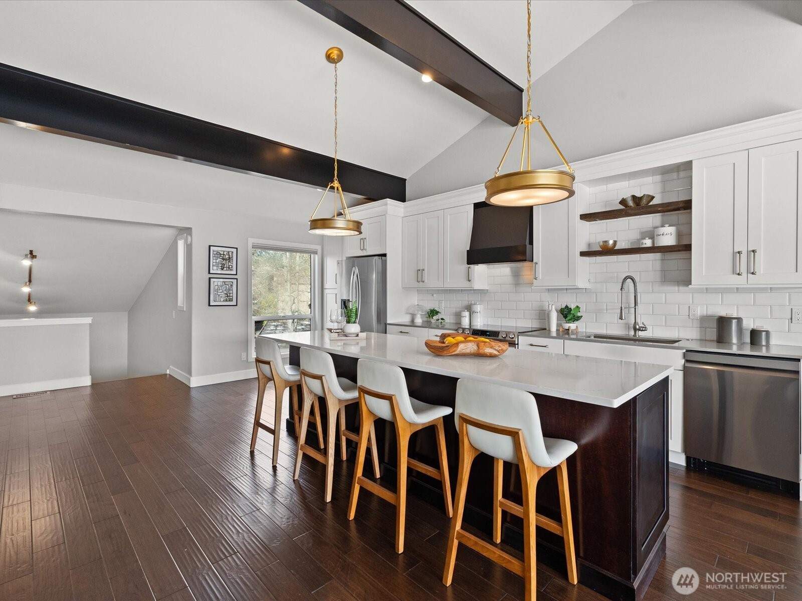 Updated kitchen with large island seating, stainless steel appliances, tile backsplash, and vaulted ceilings with exposed beams