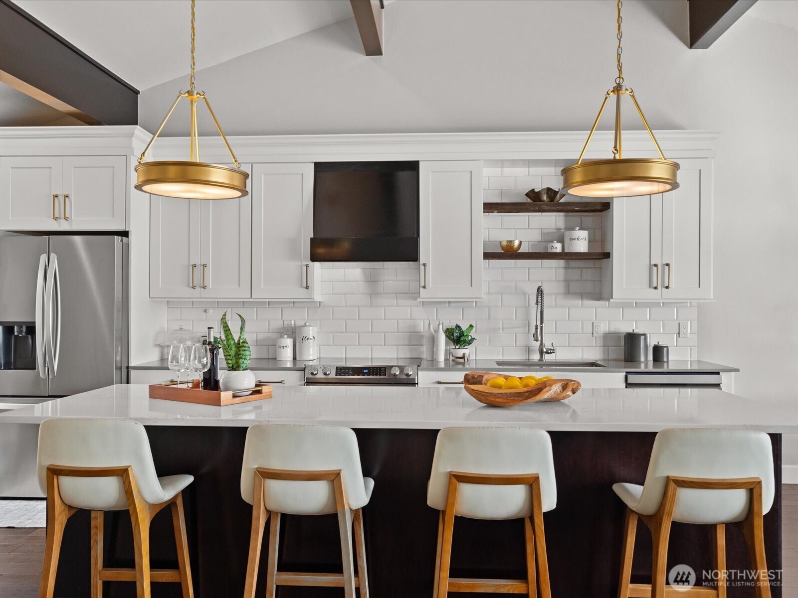Kitchen with quartz countertops, island seating, tile backsplash, and stainless steel appliances
