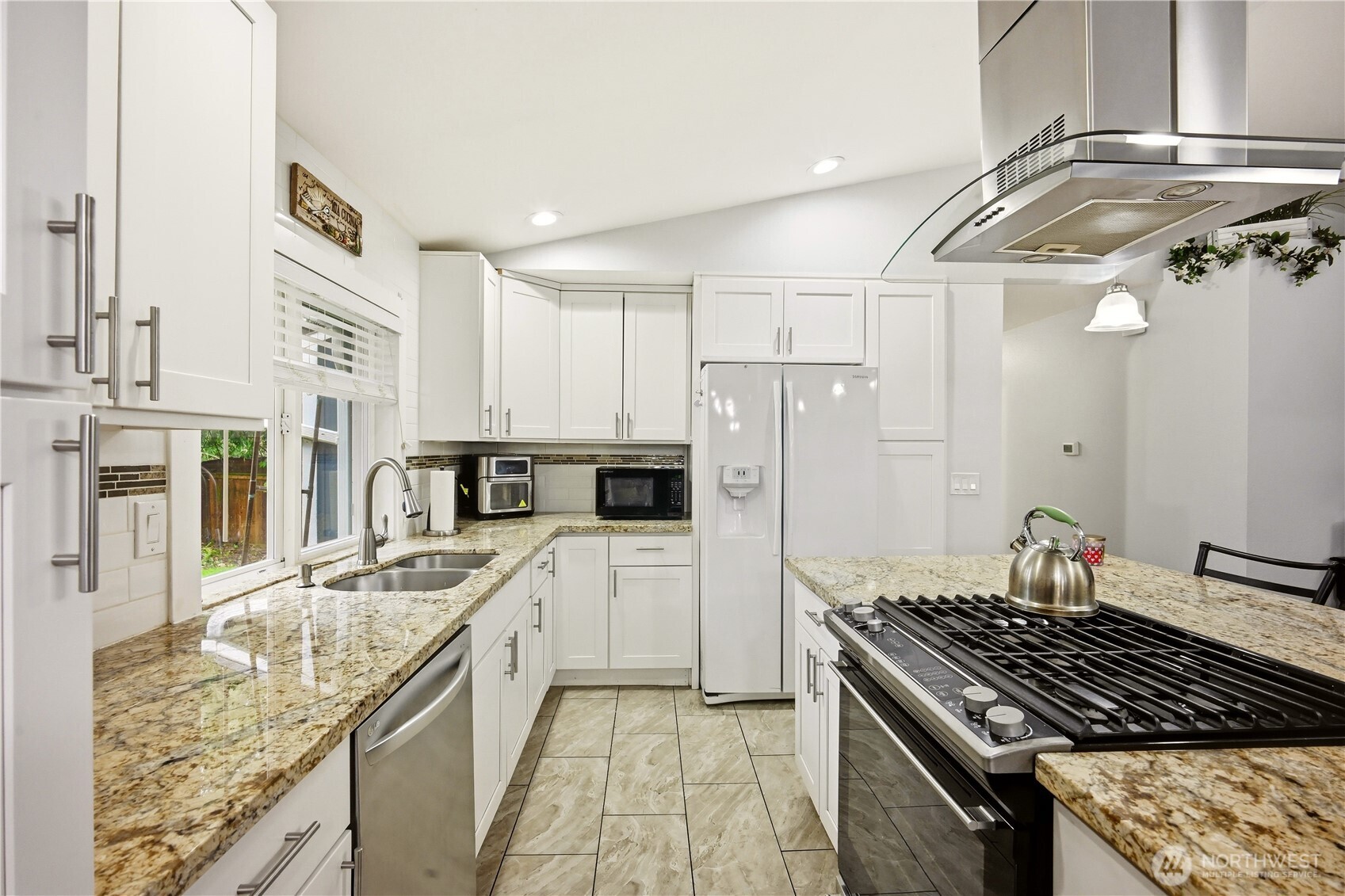 Kitchen with a modern gas range, ample prep space, sleek granite countertops and stainless steel appliances.