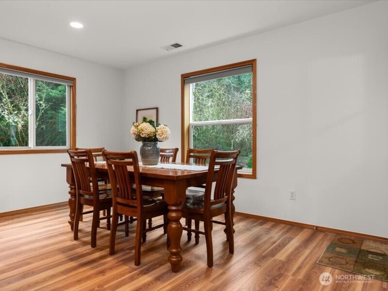 Nature wrapped, kitchen eating nook with windows on two sides, creating light and scenic backyard views