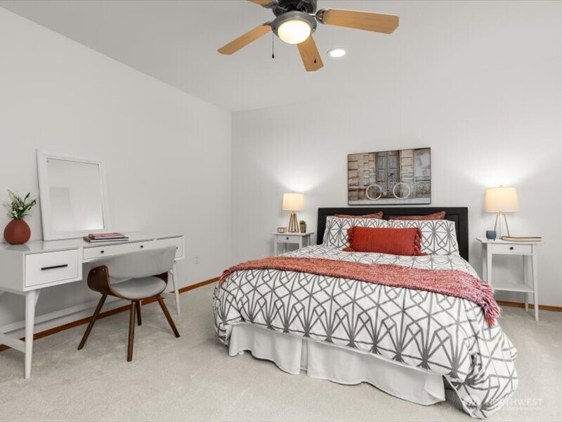 Generous secondary bedroom with walk-in closet and ceiling fan, appointed with plush new carpeting, accommodates a queen-sized bed and dresser