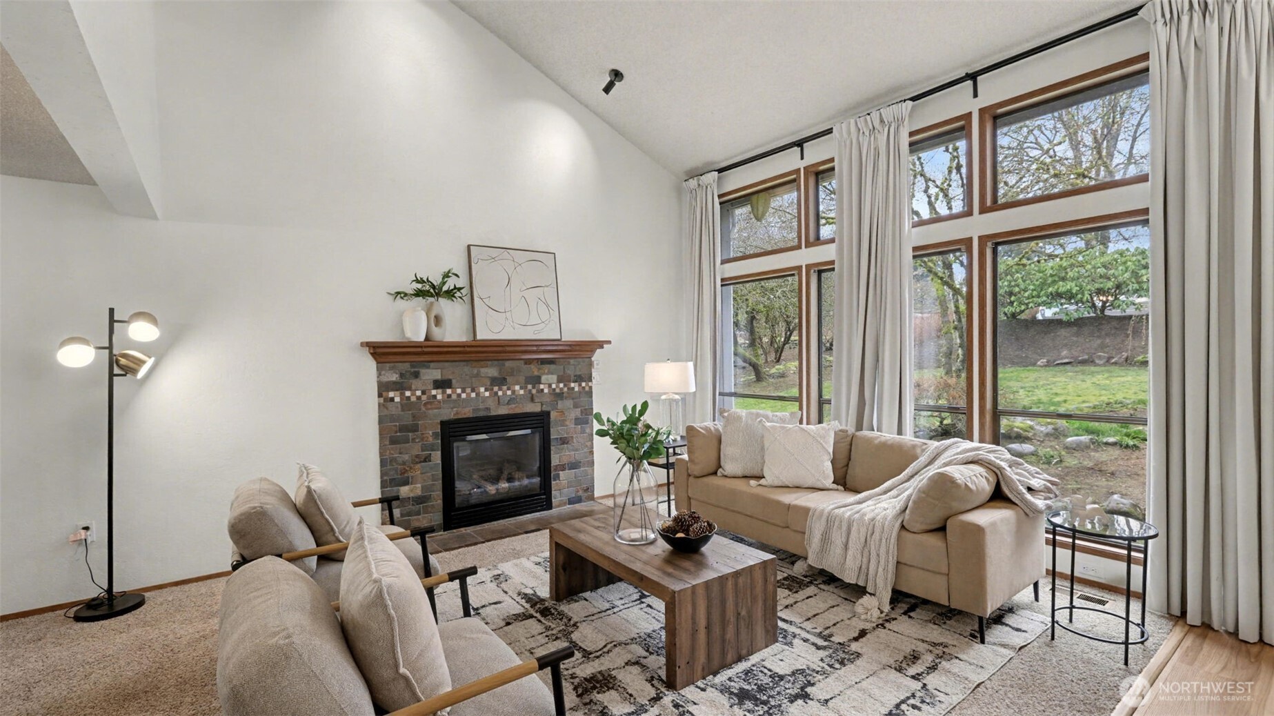 A cozy yet elevated living space featuring a statement fireplace and walls of windows that bring the outdoors in.
