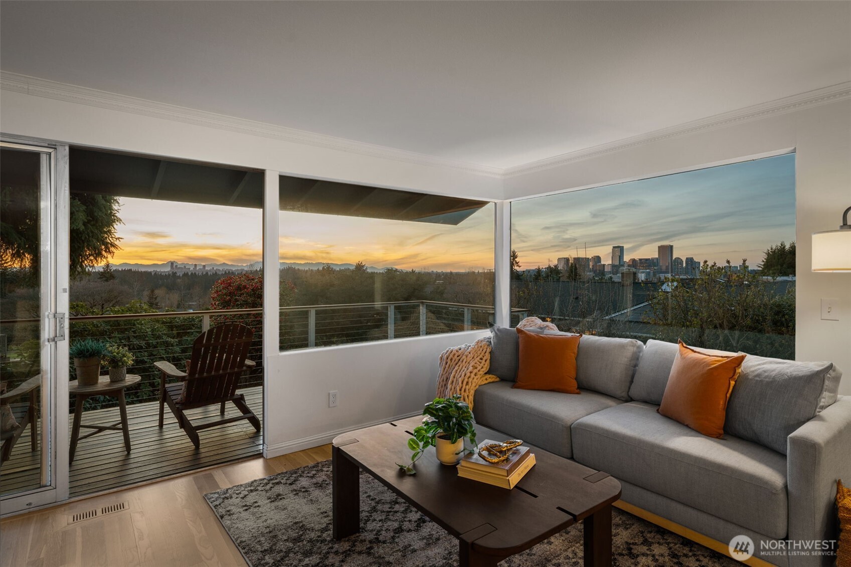 Walls of windows frame breathtaking sunset views, filling the living space with warm natural light and showcasing sweeping vistas of Bellevue, Seattle, and the Olympic Mountains.