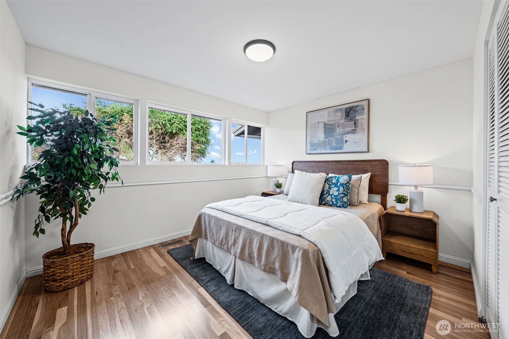 Bedroom Three features a wide window layout and peaceful outlooks. Hardwood flooring and a closet with professional organizer system make storage simple and efficient.