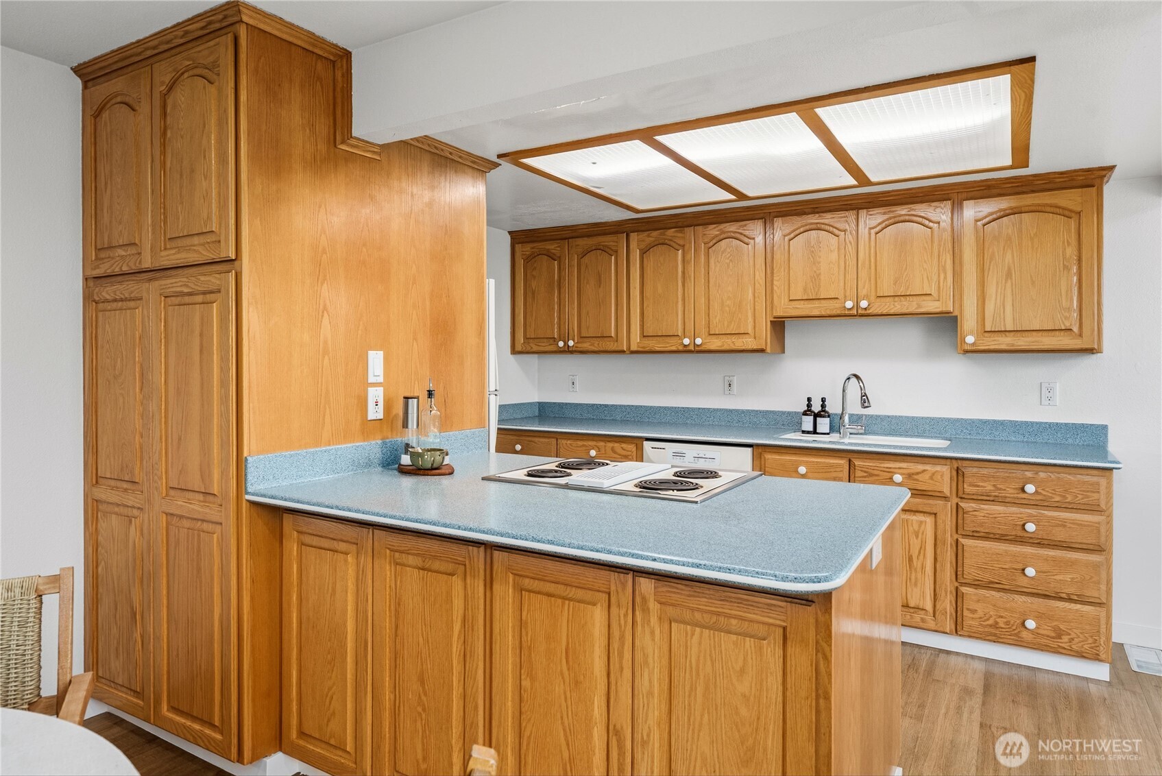 Updated living room with wide plank LVP flooring, beautiful sunset view and faux concrete floor to ceiling log fireplace.