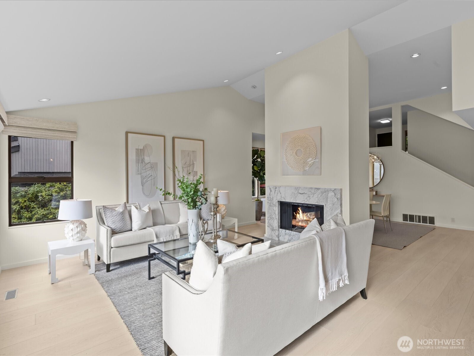 Inviting living room featuring new flooring, fresh paint, and a cozy wood-burning fireplace with a convenient gas starter. Remoted controlled shades throughout the home.