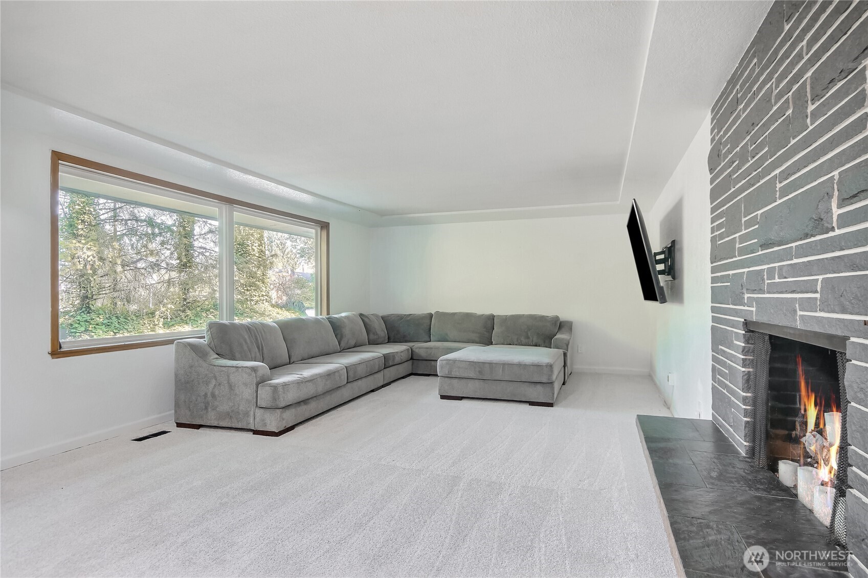 Open large living room with ambient lighting and beautiful stone fireplace with stone hearth.