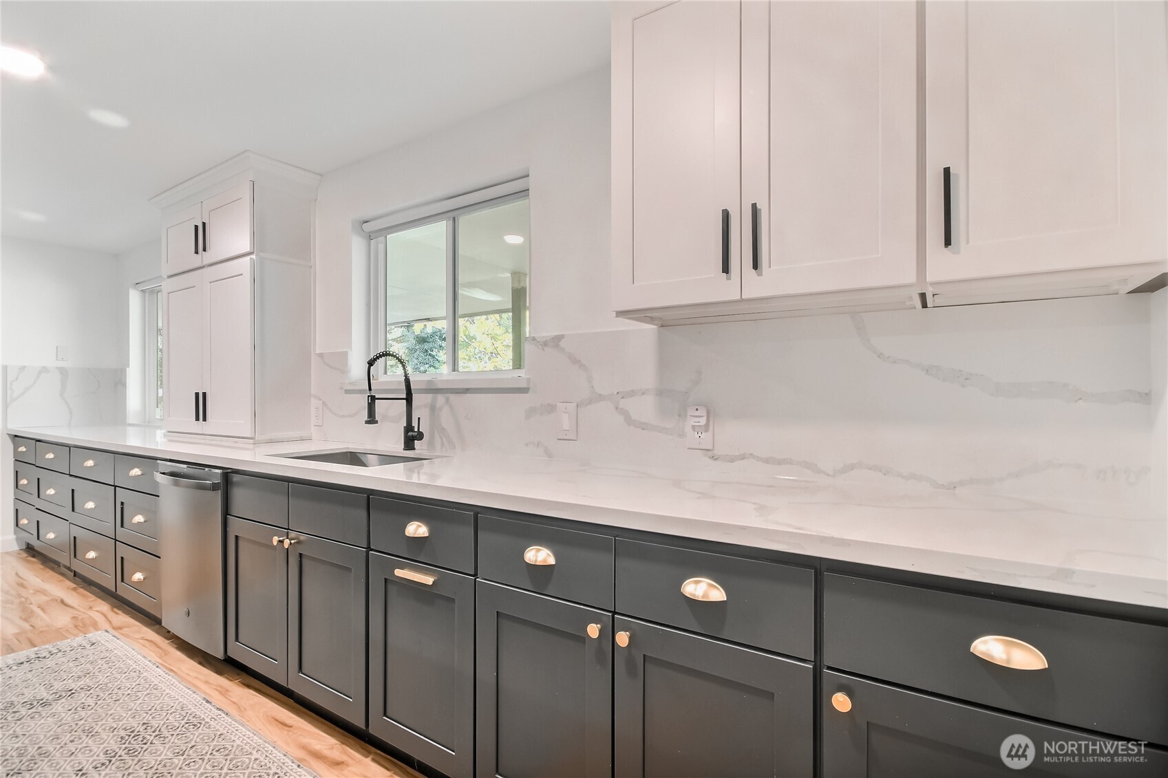 A large modern chef’s kitchen features an open layout with sleek cabinetry, a spacious island with bar seating, stainless steel appliances, and quartz countertops. Ample storage, and built-in refrigeration make it functional, while minimalist design, clean lines, and statement lighting add a sophisticated, contemporary look.