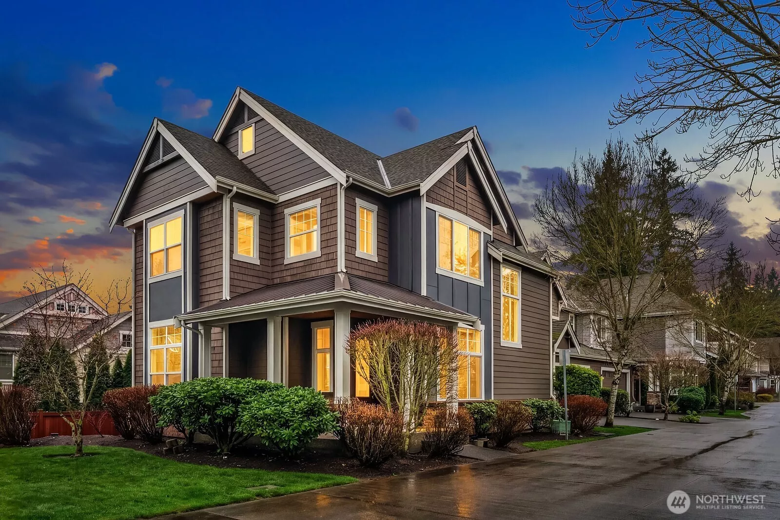 This stunning Craftsman-style home makes an unforgettable first impression at dusk, showcasing beautiful curb appeal with its classic architecture, warm glowing windows, and lush mature landscaping on a coveted corner lot in Sycamore Park.