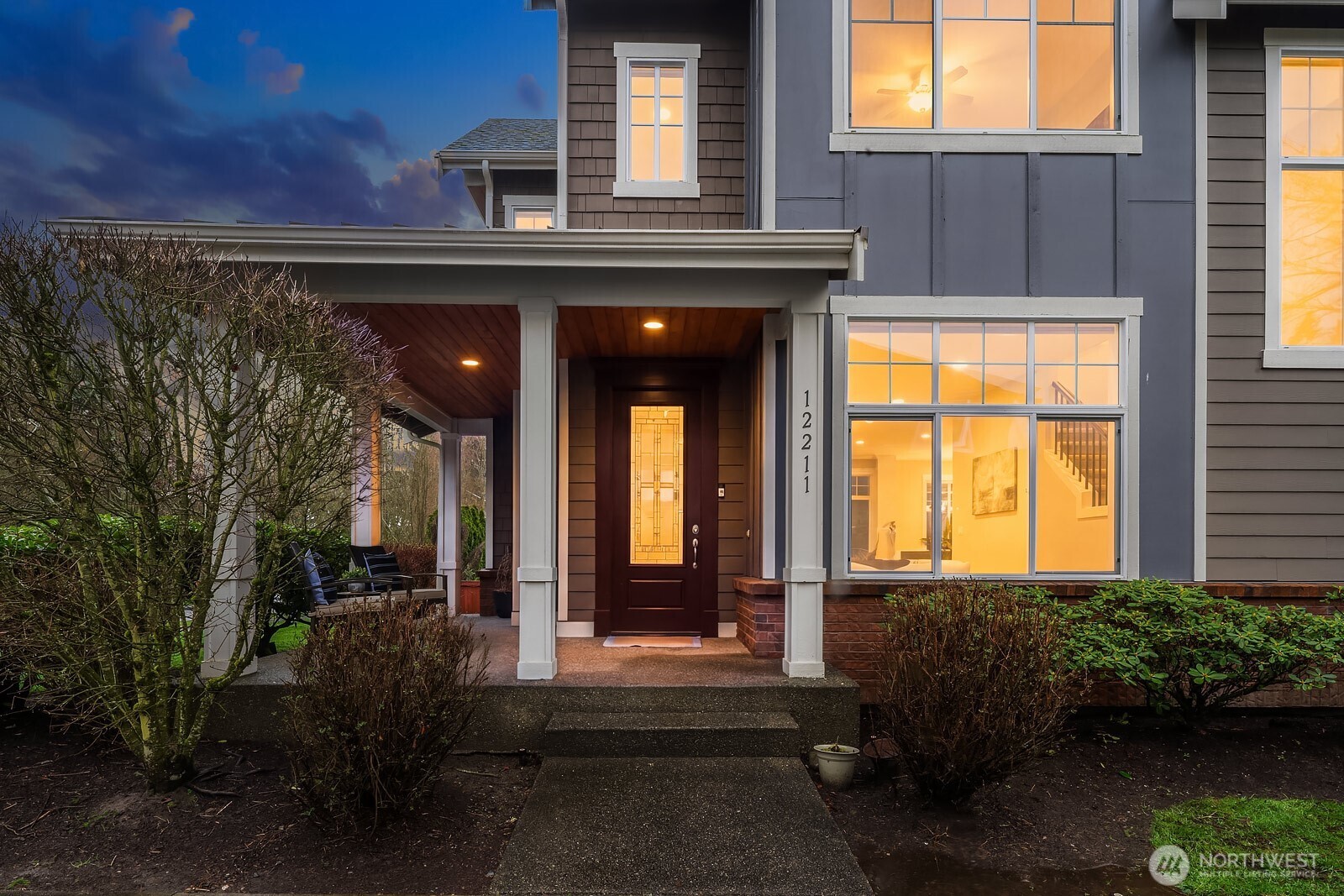 This stunning Craftsman-style home makes an unforgettable first impression at dusk, showcasing beautiful curb appeal with its classic architecture, warm glowing windows, and lush mature landscaping on a coveted corner lot in Sycamore Park.