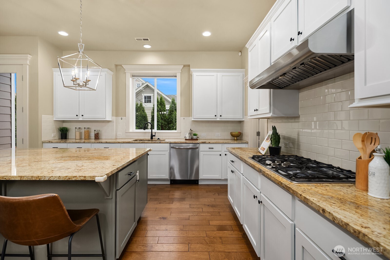 This angle showcases the kitchen's premium gas cooktop, classic subway tile backsplash, and stone countertops — beautifully crafted details that elevate this space into a truly high-end culinary experience.