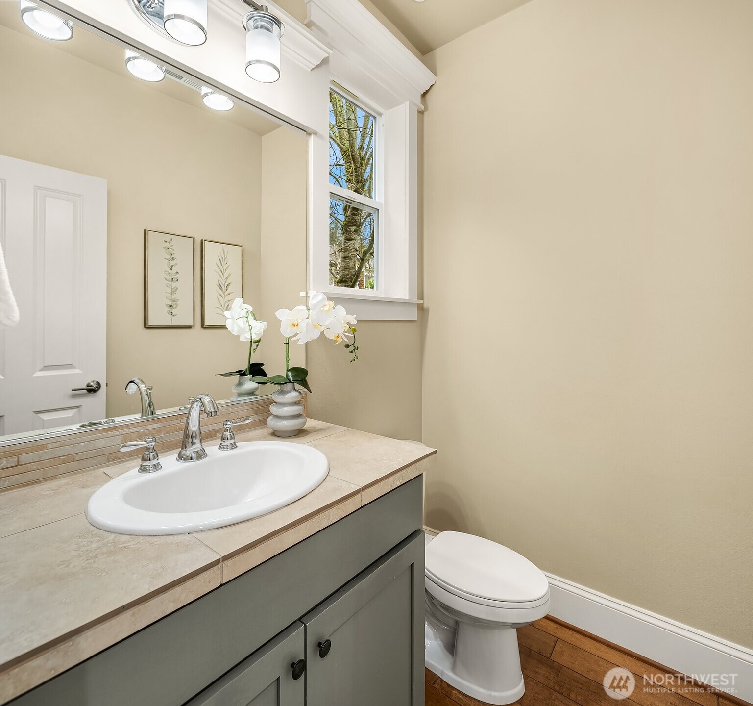A stylish powder room on the main level features a warm vanity with classic finishes and a large mirror — a polished and practical space for guests and everyday use.