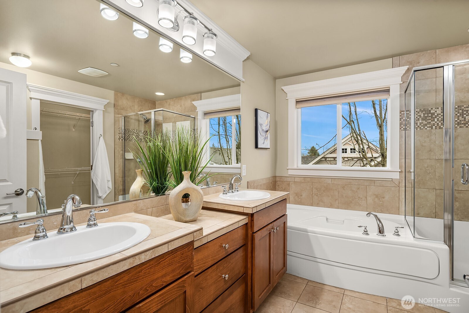 The spa-inspired five-piece primary bath features double vanities, a soaking tub, and warm wood cabinetry — a luxurious and beautifully appointed retreat designed for rest and rejuvenation.