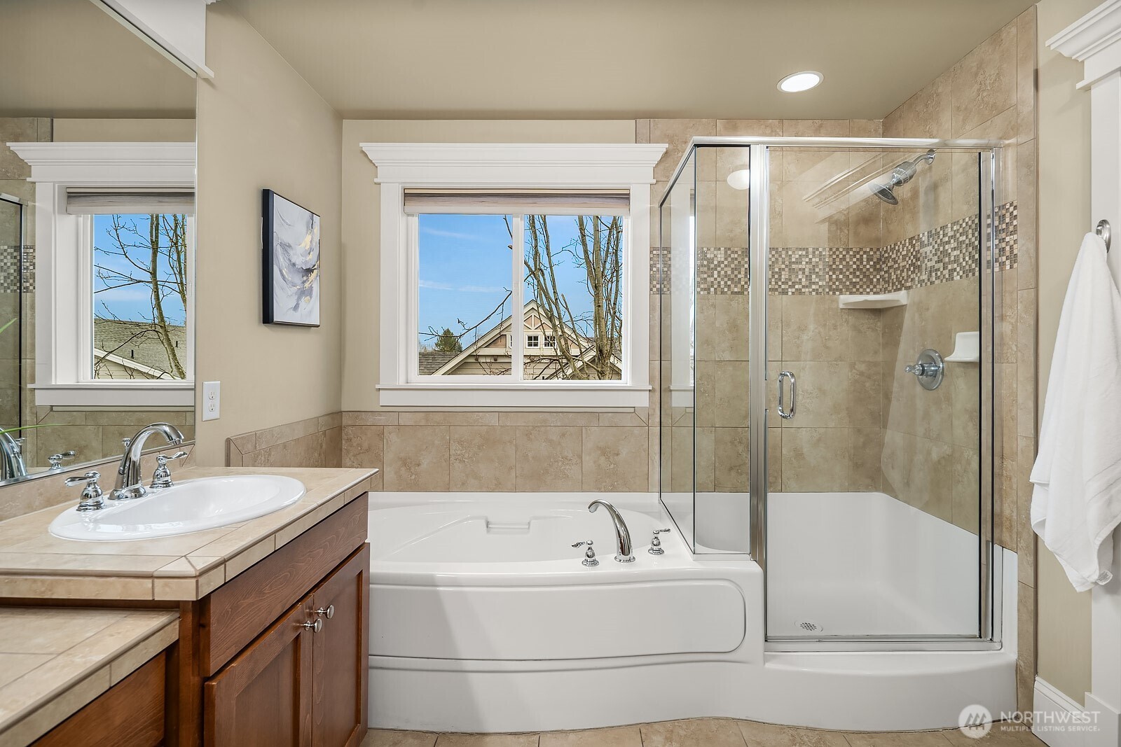 Another angle of the primary bath highlights the elegant soaking tub, glass-enclosed shower, and bright window — a thoughtfully designed and indulgent space that completes this exceptional primary suite.