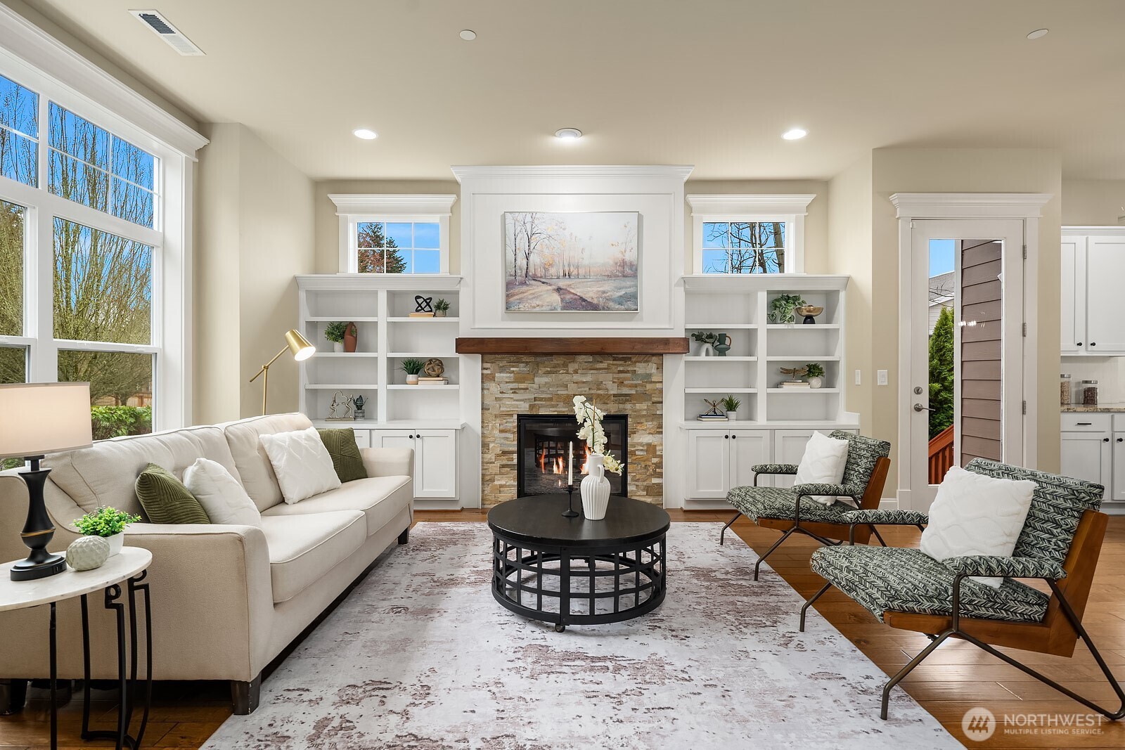 The inviting living room is a showstopper, featuring vaulted ceilings, oversized windows flooding the space with natural light, a cozy gas fireplace, and elegant custom built-ins — a perfect blend of comfort and sophistication.