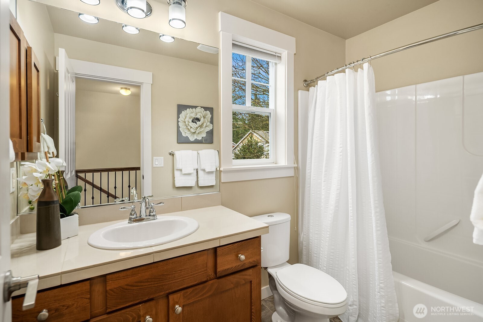 The full secondary bath features a shower/tub combo, warm wood vanity, and classic finishes — a clean and well-appointed space serving the upper level bedrooms with ease.