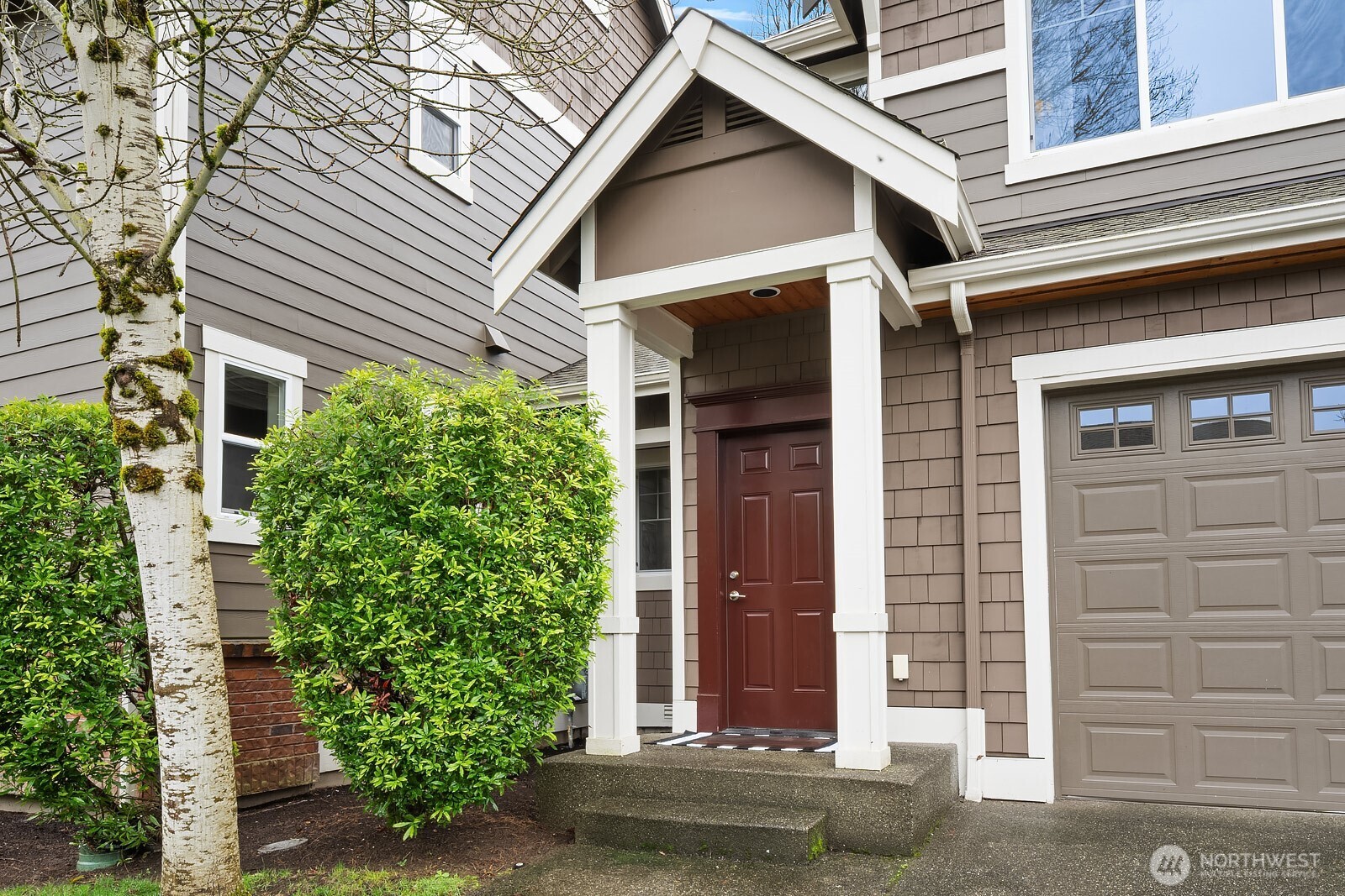 The welcoming front entry features a classic covered portico, warm wood door, and lush surrounding greenery — a charming and polished first impression that sets the tone for the quality found throughout this exceptional home.