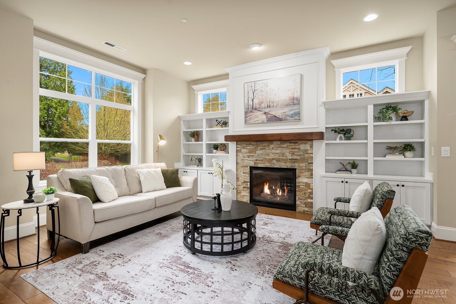 Another angle of the living room highlights the generous layout, abundant natural light, and the beautifully appointed fireplace flanked by custom built-ins — a warm and elegant space designed for both relaxing and entertaining.
