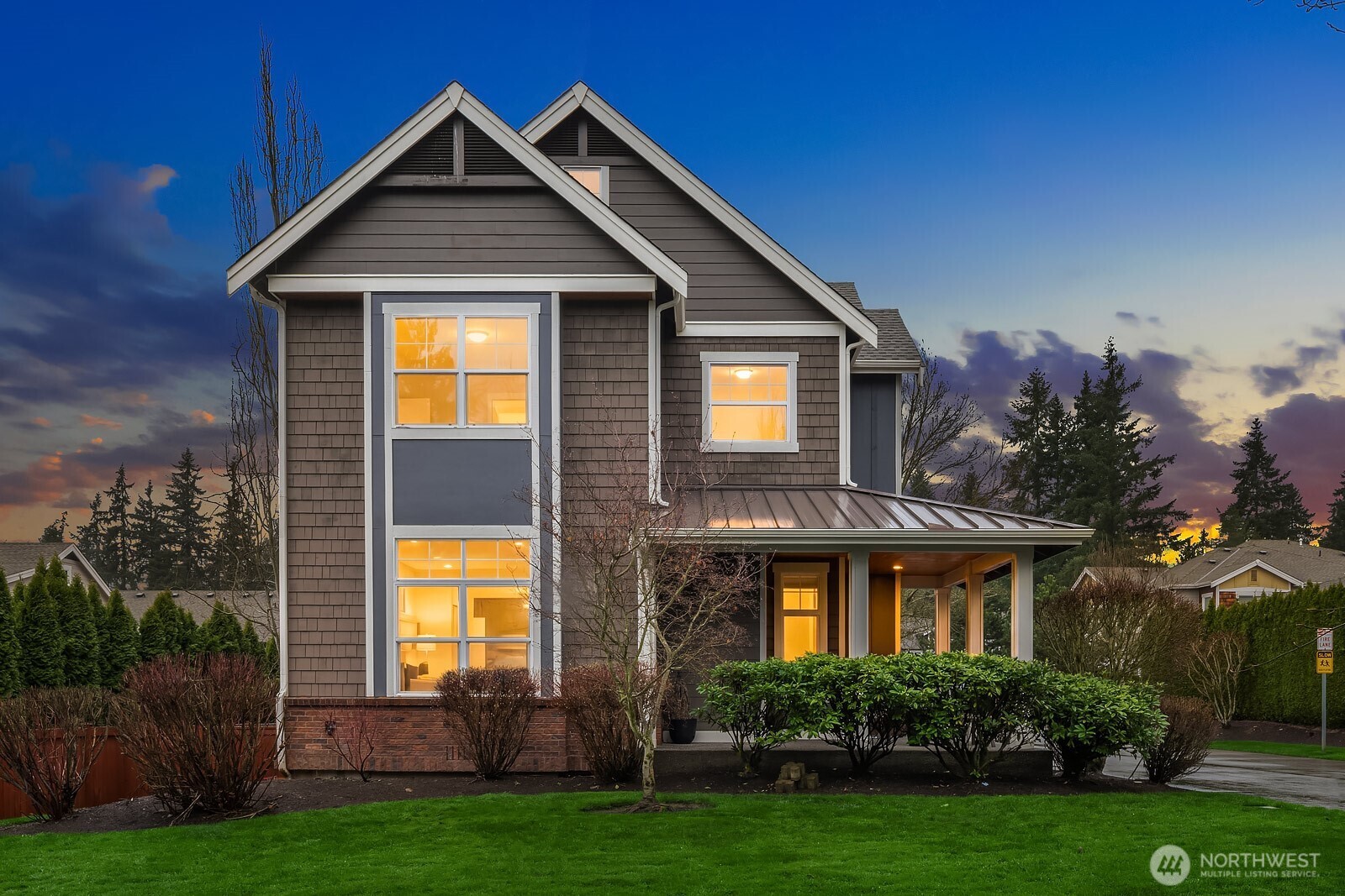 A breathtaking dusk shot captures the home's stunning curb appeal, with warm light glowing from within, classic Craftsman architecture, and lush landscaping — a truly picture-perfect welcome to this exceptional Sycamore Park property.