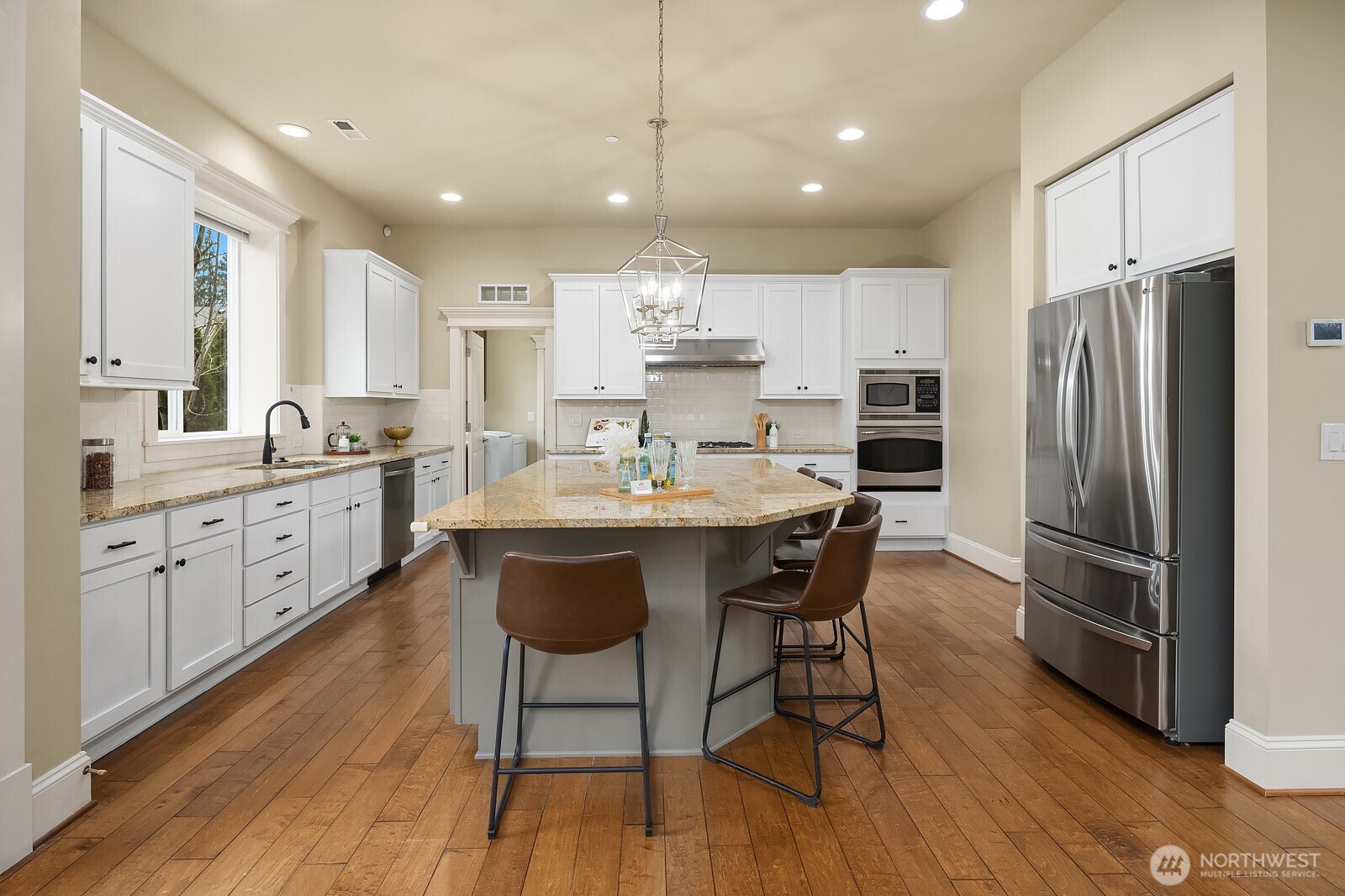 This view of the kitchen highlights the thoughtful layout with ample counter space, high-end stainless steel appliances, and rich hardwood flooring — a polished and practical space at the true heart of the home.