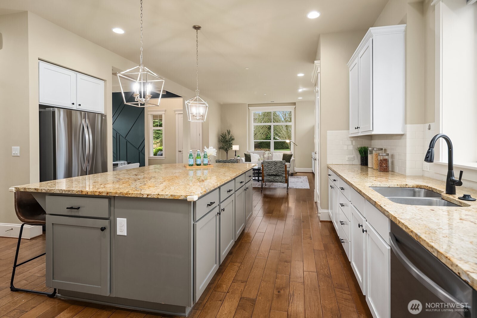 A closer look at the kitchen's wraparound island and farmhouse-style sink highlights the premium finishes and thoughtful design details, with an open sightline into the living areas beyond that makes this space as connected as it is beautiful.
