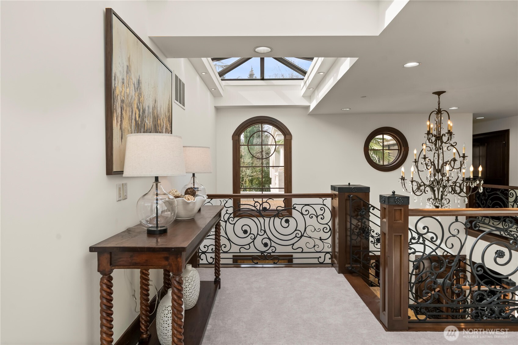 Light-filled upper landing featuring a skylight, custom wrought-iron railing, and refined architectural details.