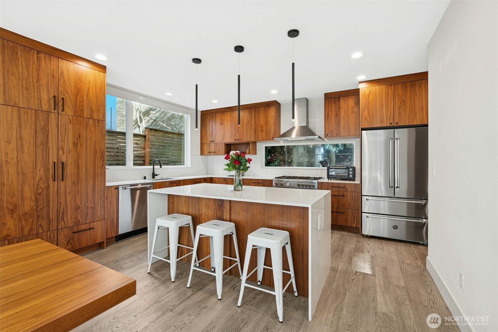 Chef’s island kitchen features rich walnut cabinetry, quartz slab counters, & high-end stainless-steel appliances