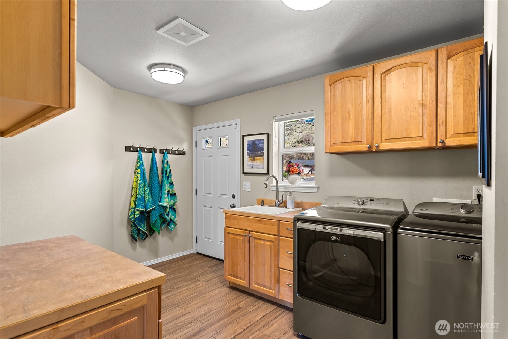 Spacious utility room with washer and dryer included, featuring a laundry sink, ample storage, and direct exterior access.