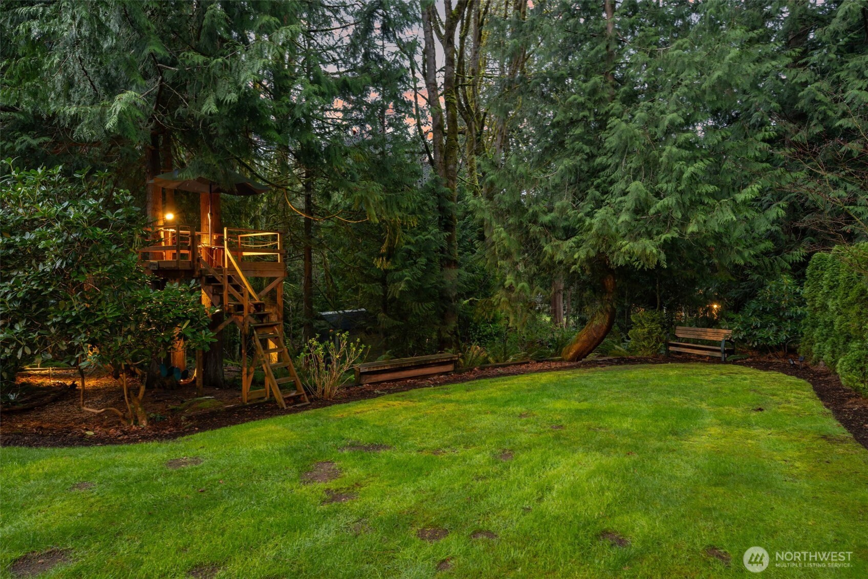 Custom tree house with swing set and exterior lighting.