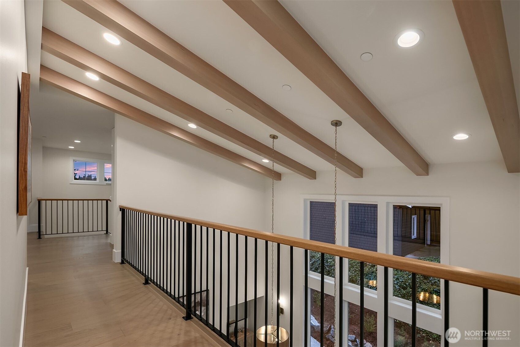 Mezzanine-style upper walkway overlooking the dining area, featuring exposed beams and open railings that enhance light and connection.