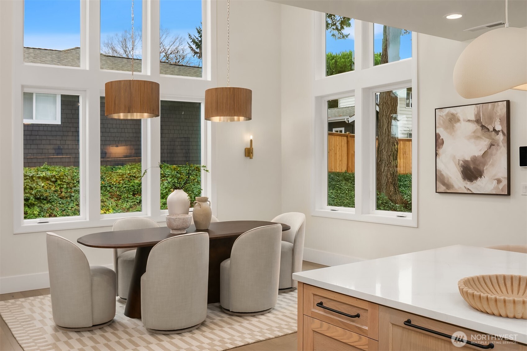 Light-filled dining area featuring soaring over 18 foot ceilings and open sightlines visible from the upper level.