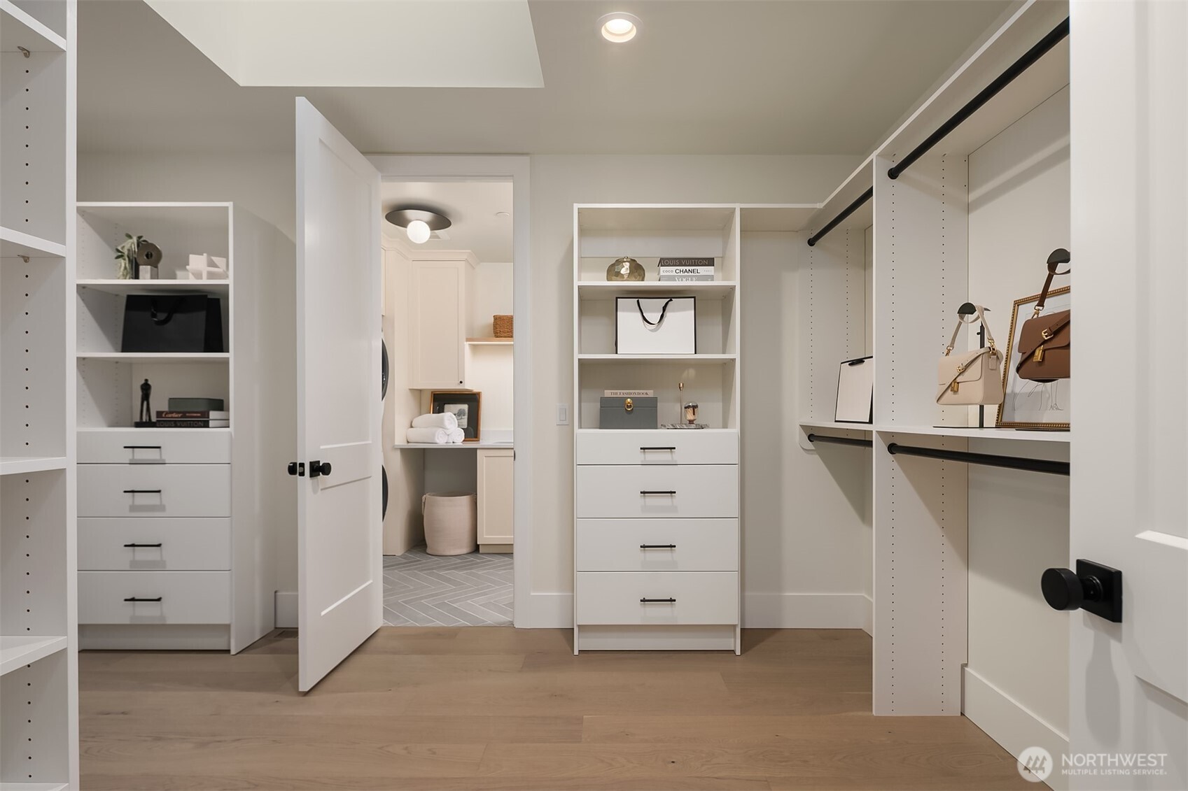 An expansive primary walk-in closet designed like a private boutique, featuring custom built-ins, generous hanging and storage, and direct access to the laundry room featuring Electrolux washer and dryers for effortless daily living.