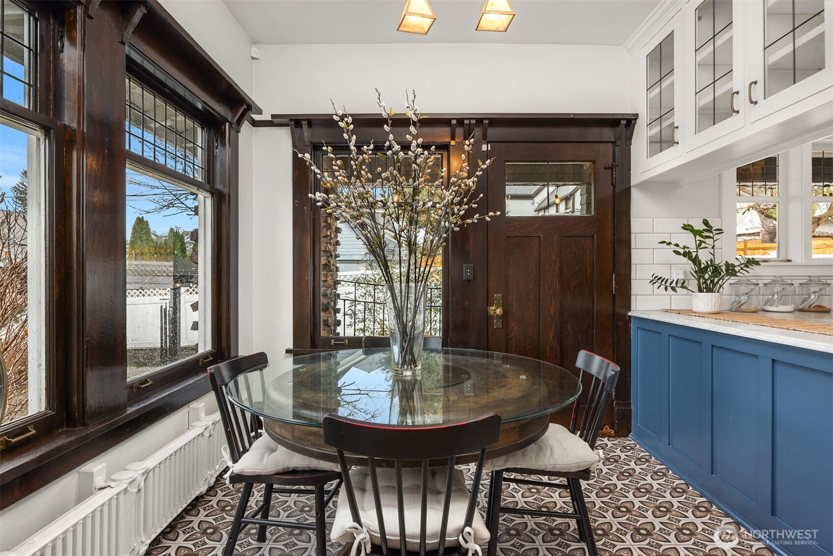 A thoughtfully renovated kitchen blends historic charm with modern design. Custom cabinetry in a rich blue tone, marble-style counters, and period-inspired lighting connect seamlessly to the breakfast nook, creating a warm, functional heart of the home.
