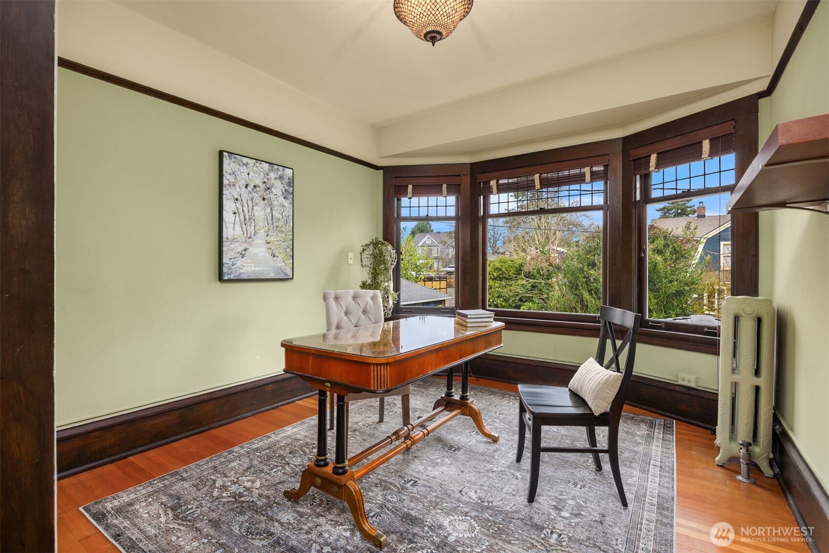 A versatile bedroom currently styled as a home office with walk-in closet offers flexibility without sacrificing charm. Bay windows fill the space with natural light, while original trim and hardwood floors create an inspiring setting equally suited for remote work, a guest room, or a private retreat.