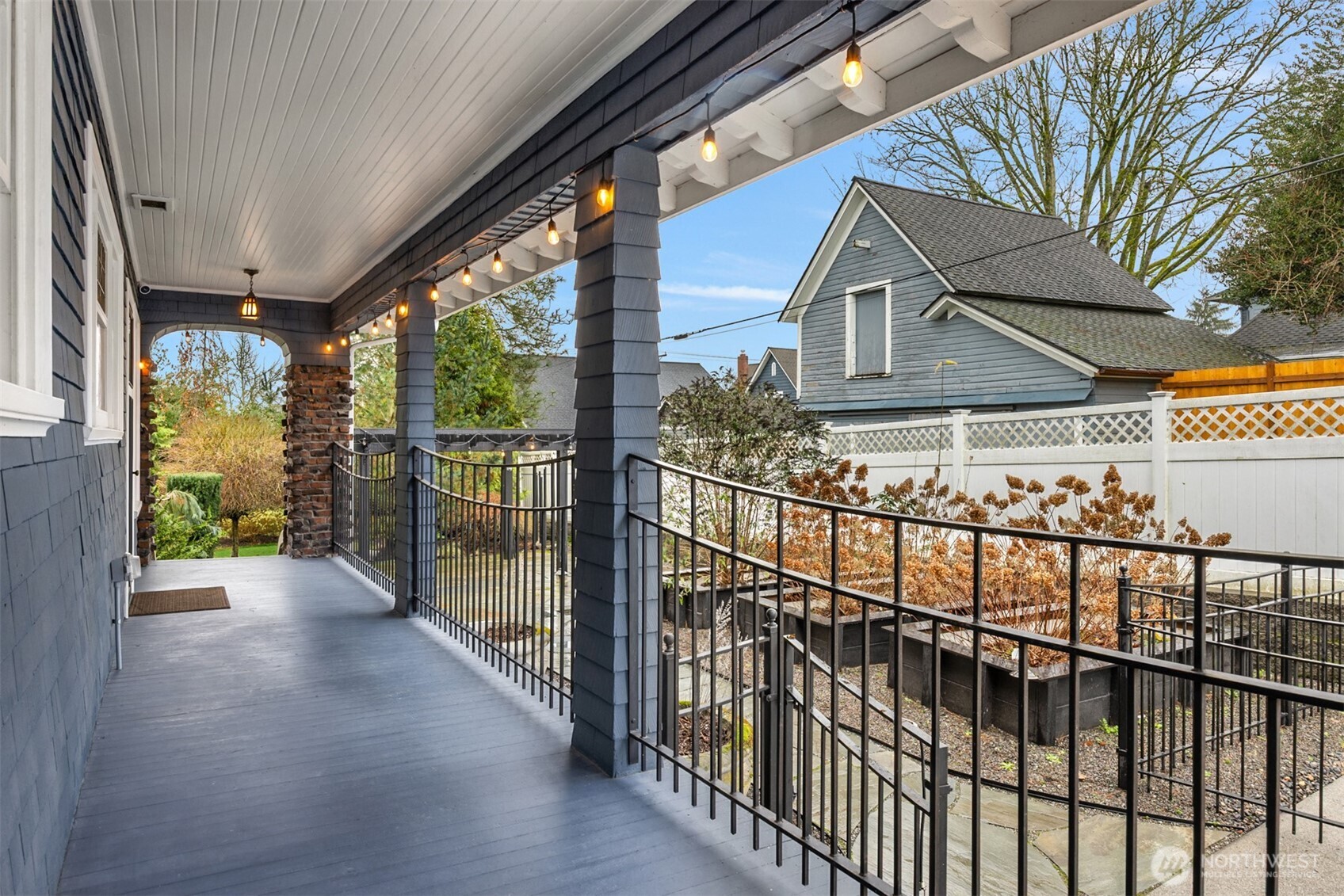 A covered side porch enhances everyday living, providing a sheltered transition between indoor spaces and the garden below.