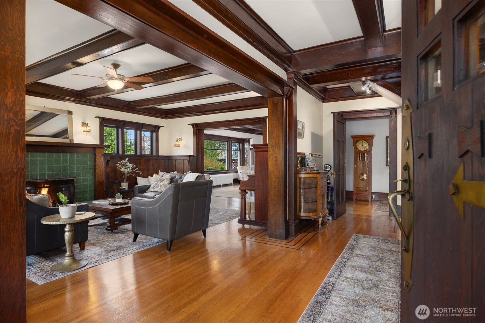 A grand introduction unfolds from the moment you step inside. Richly stained coffered ceilings, original millwork, and glowing hardwoods frame an elegant living space anchored by a classic fireplace—setting the tone for a home defined by authenticity and architectural integrity.