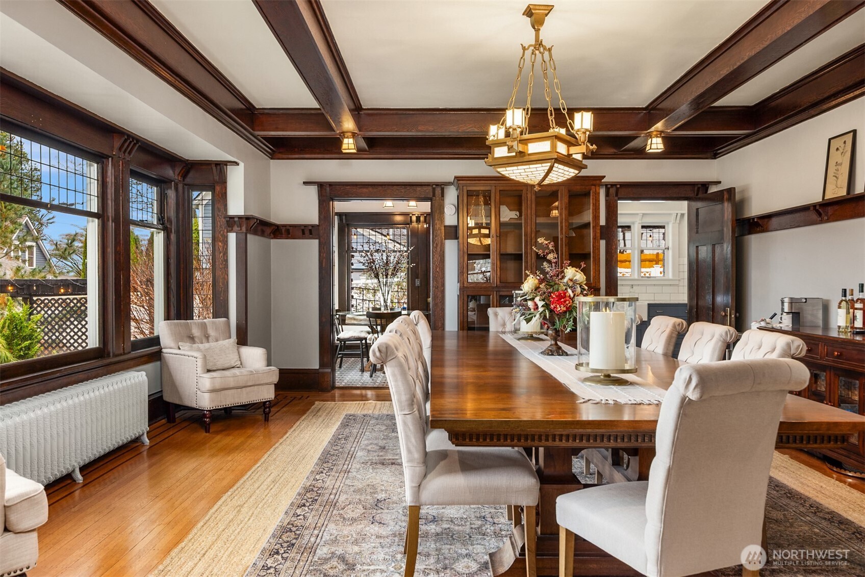A charming breakfast nook blends historic character with modern function. Original wood-trimmed windows, patterned tile floors, and a cozy built-in feel create an inviting space for morning coffee or casual meals, seamlessly connected to the kitchen while overlooking the garden beyond.