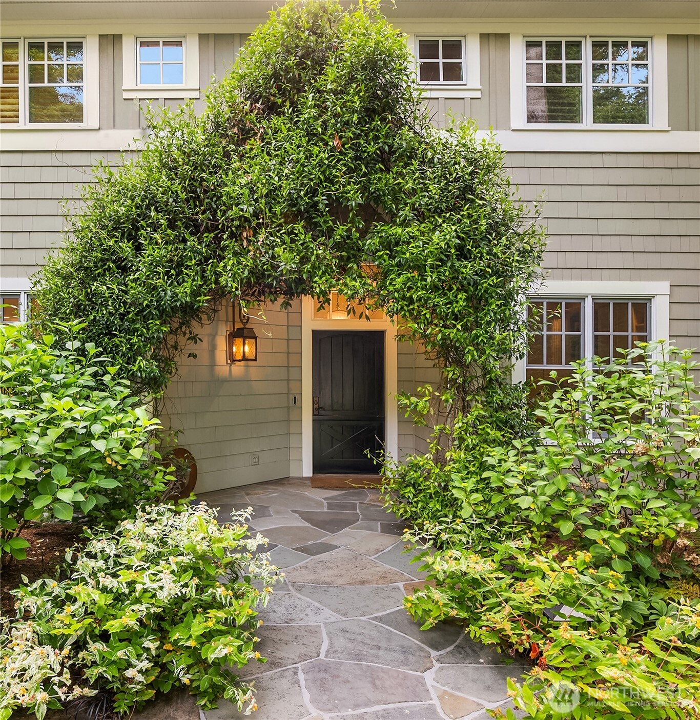 Flagstone walkway leads to an arched entry draped in jasmine vine.