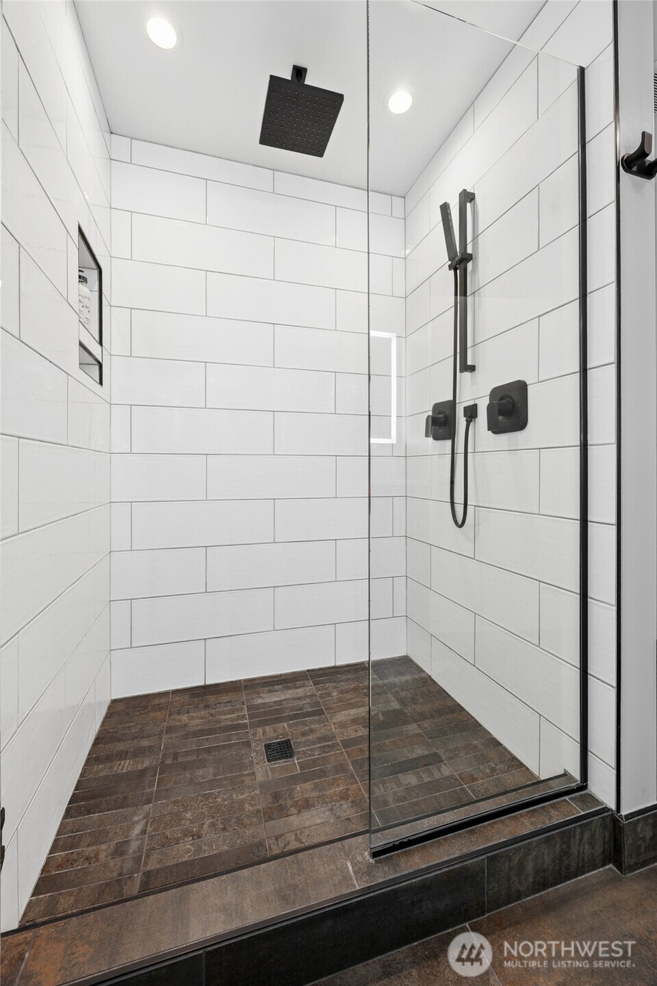 The shower stall has waterfall faucet heads and a built-in caddy for your bath products.
