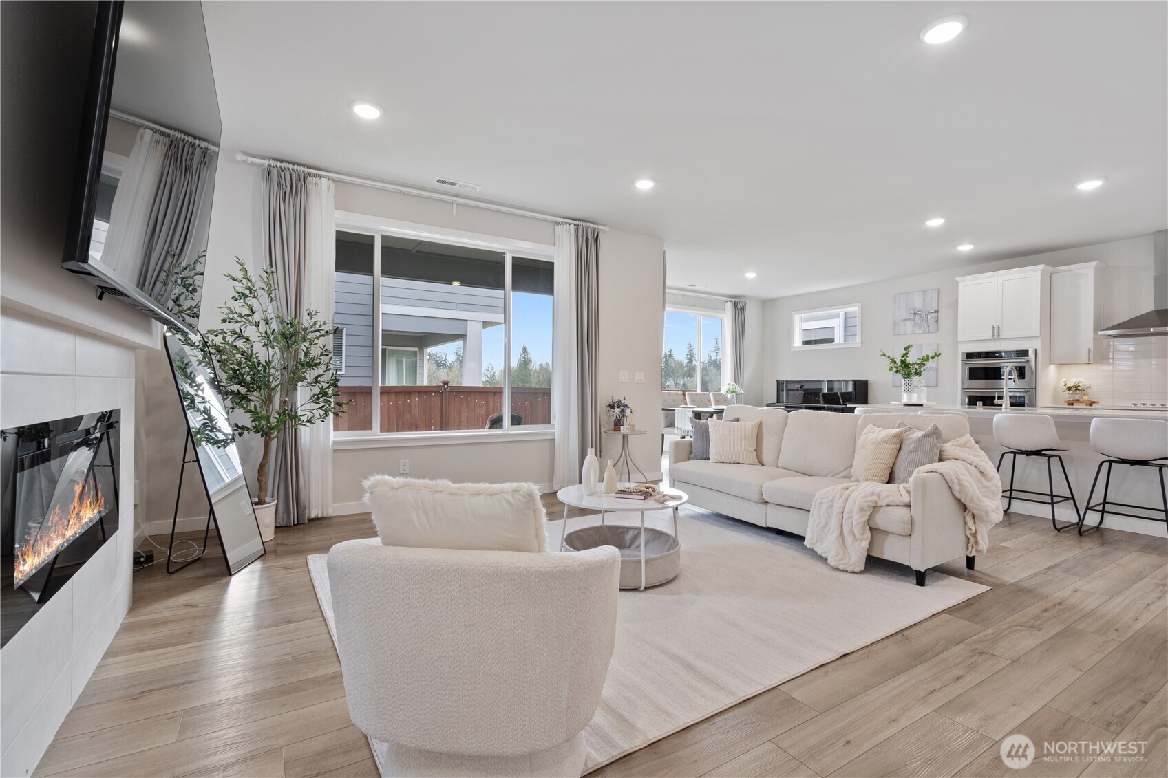 Sun-drenched open-concept living space where soaring windows meet modern comfort, creating an inviting heart of the home.