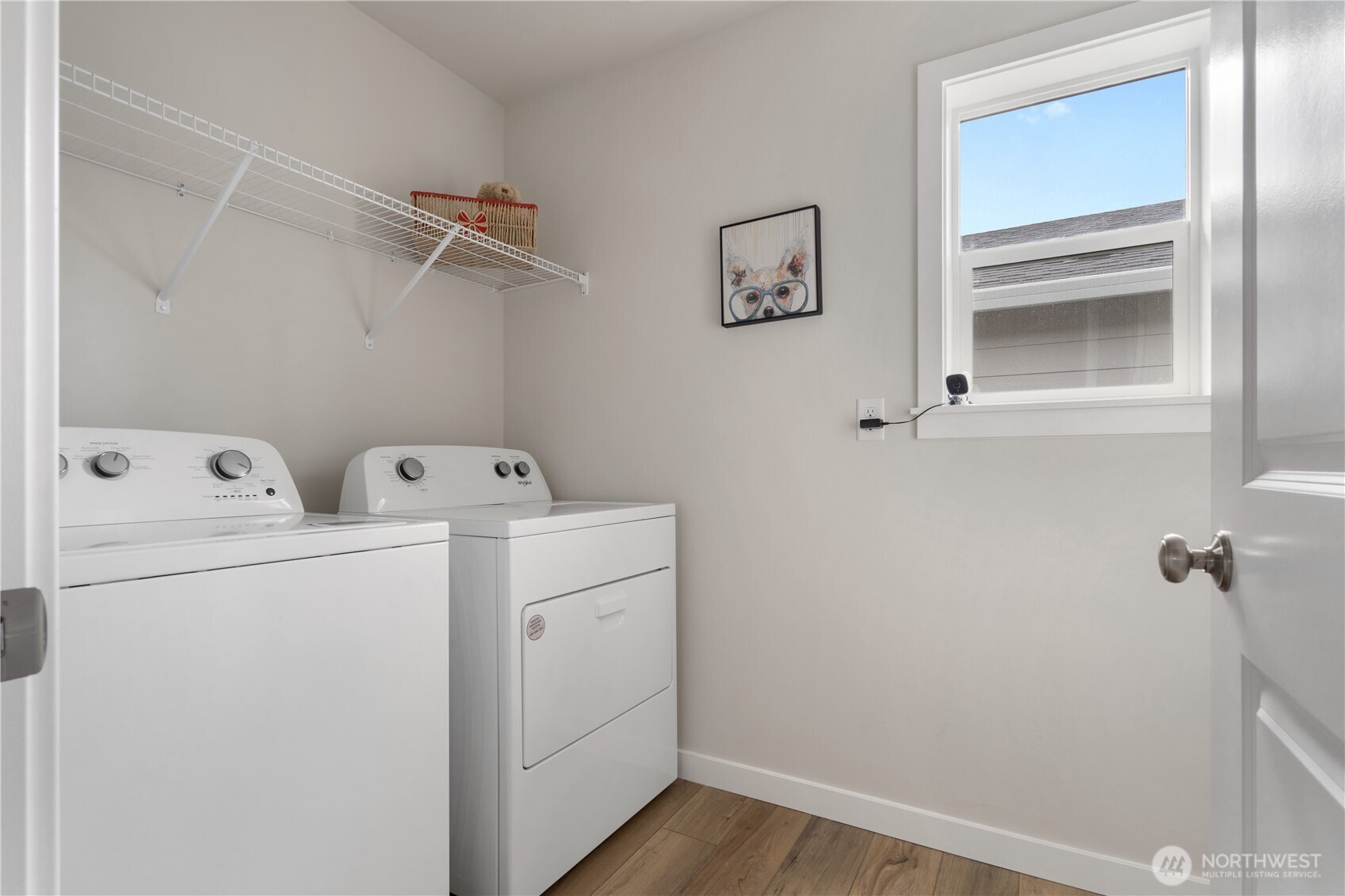 Upper-level laundry room with side-by-side washer/dryer and storage shelf.