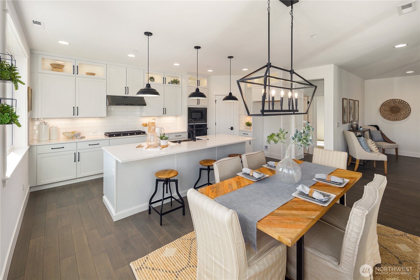 Kitchen & Dining  This open concept kitchen and dining area is designed for seamless flow and modern Northwest living in Bothell’s Canyon Park area. A quartz island with seating anchors the space, framed by full-height cabinetry, a gas cooktop, wall oven, and under-cabinet lighting. Statement pendant lighting defines the dining zone while expansive windows bring in natural light, highlighting wide plank flooring and clean architectural lines. The layout supports effortless gathering and everyday function, reflecting the elevated finishes expected in luxury new construction within the Northshore School District.    These photos are from a past Robinson Plan at a different community, so overall plan, colors, building orientation, finishes, home outlook, and other details can and WILL vary. All photos, renderings, site maps, and floorplans are for visualization purposes only.