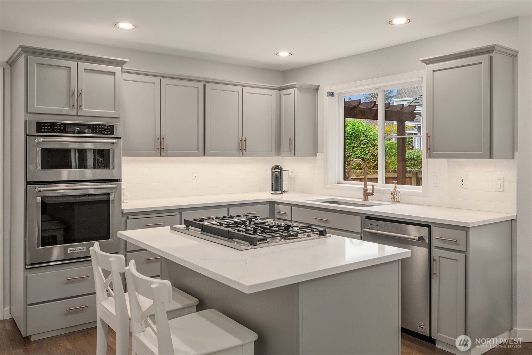 Kitchen features gas range with down draft, slab quartz counters with under-mount stainless trough sink.