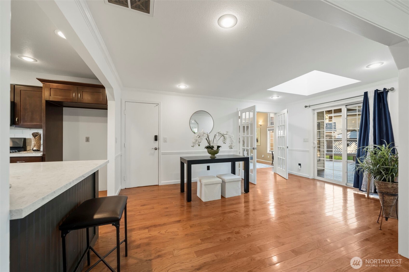 Looking into the secondary great room opens with vaulted ceilings and abundant windows, while skylights throughout the dining area and home bring in beautiful natural light. Sliding glass door leads directly to the expansive deck, extending the living space outdoors for easy entertaining.